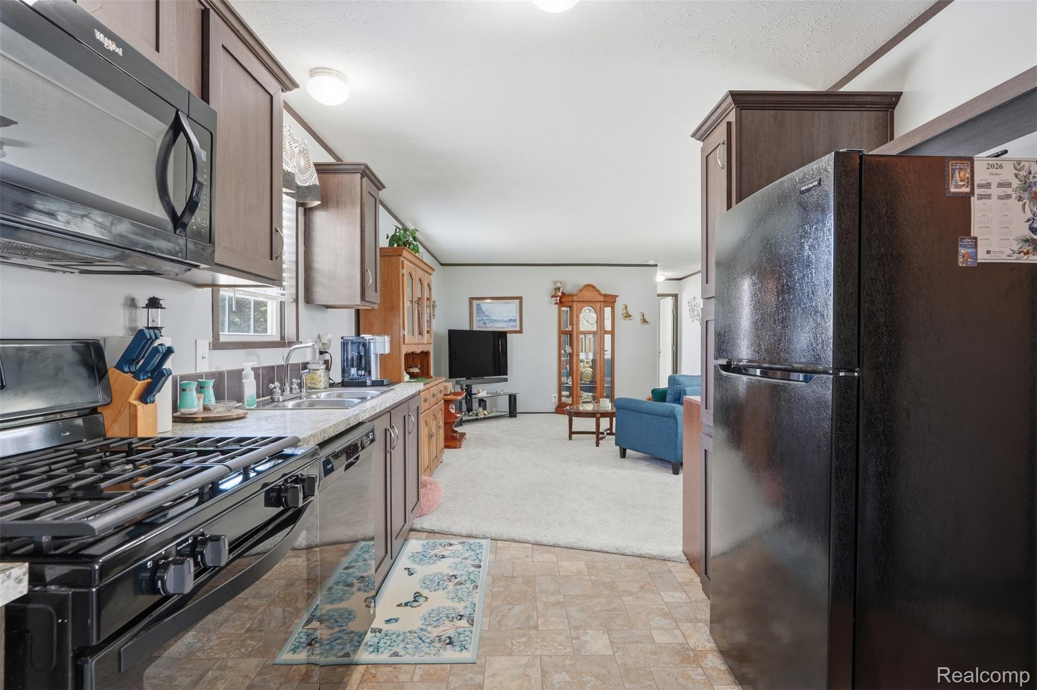 440 Flamingo Street Rochester, MI 48309 - Photo 17 of 32 Kitchen with black appliances, light carpet, stone finish floors, dark wood finish cabinetry, and light stone countertops
