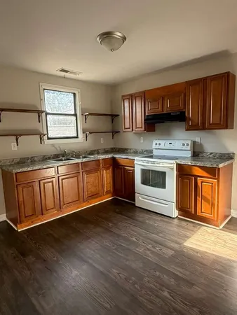 a kitchen with stainless steel appliances granite countertop wooden cabinets a sink and dishwasher a refrigerator with wooden floor