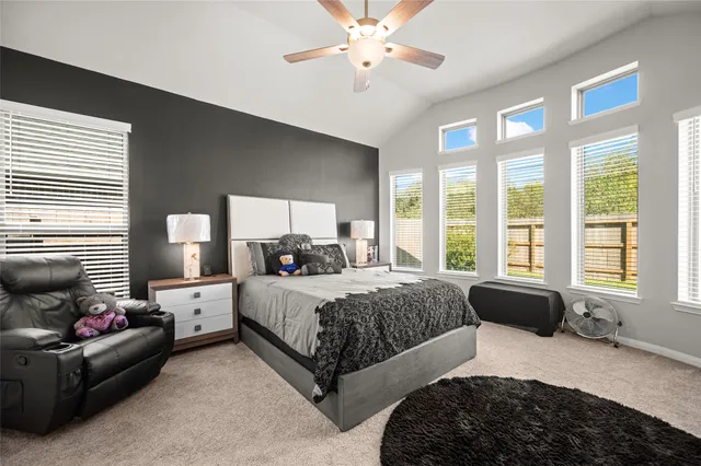 a bedroom with a bed couches and large windows