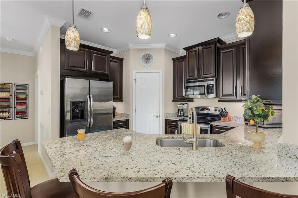 23550 Alamanda Drive, Unit 202 Estero, FL 34135 - Photo 14 of 26 a kitchen with stainless steel appliances granite countertop a stove refrigerator and cabinets
