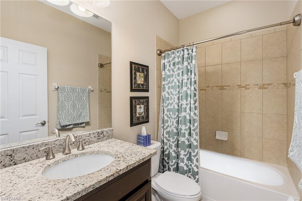 23550 Alamanda Drive, Unit 202 Estero, FL 34135 - Photo 18 of 26 a bathroom with a granite countertop sink toilet and shower