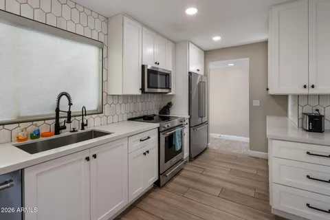 a kitchen with white cabinets and stainless steel appliances