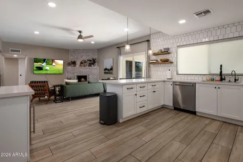 a kitchen with stainless steel appliances granite countertop a sink dishwasher a stove top oven a dining table and chairs with wooden floor