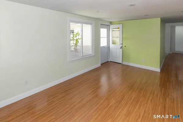 a view of an empty room with wooden floor and a window