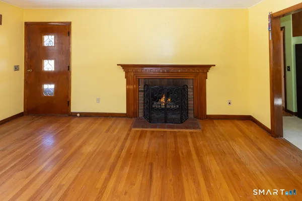 a view of an empty room with wooden floor and a fireplace