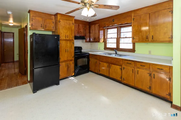 a kitchen with granite countertop a refrigerator a sink a stove and cabinets