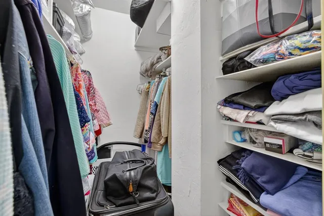 a view of walk in closet with clothes and shoes