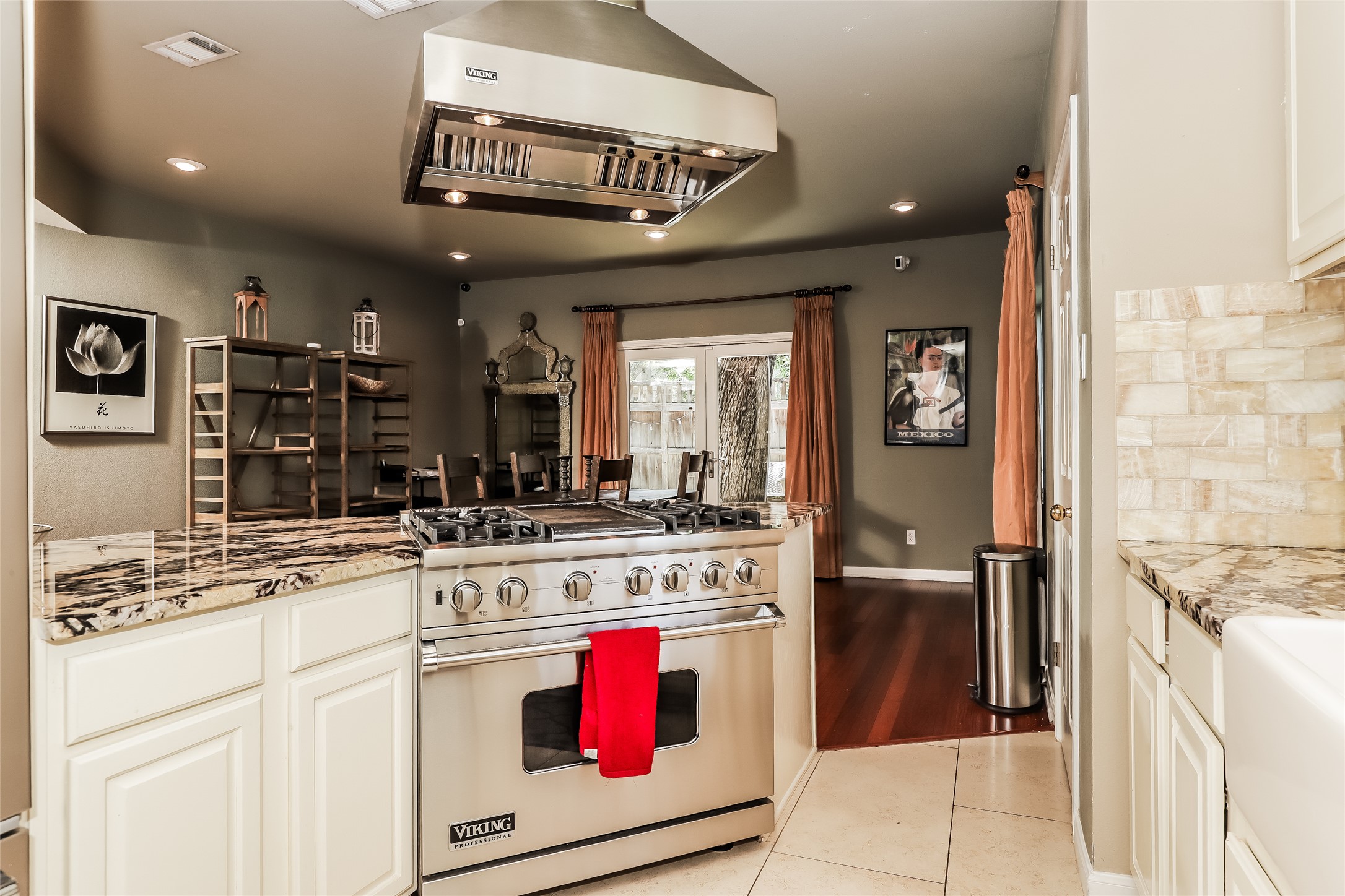 1702 Newning Avenue, Unit A Austin, TX 78704 - Photo 5 of 20 Gourmet kitchen featuring a stainless steel professional-grade range with a coordinating vent hood, granite countertops, cream-colored cabinetry, and a subway tile backsplash