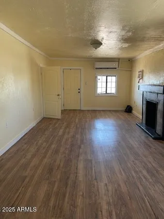 an empty room with wooden floor fireplace and windows