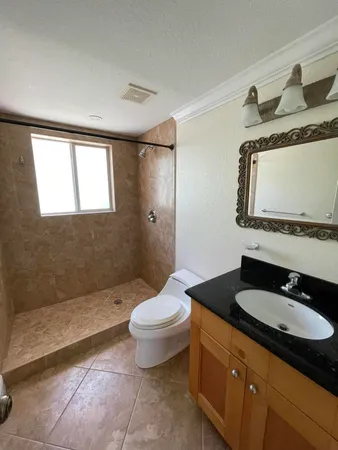 a bathroom with a granite countertop sink mirror vanity and toilet