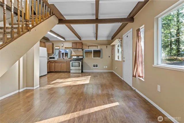 a view of empty room with wooden floor and windows