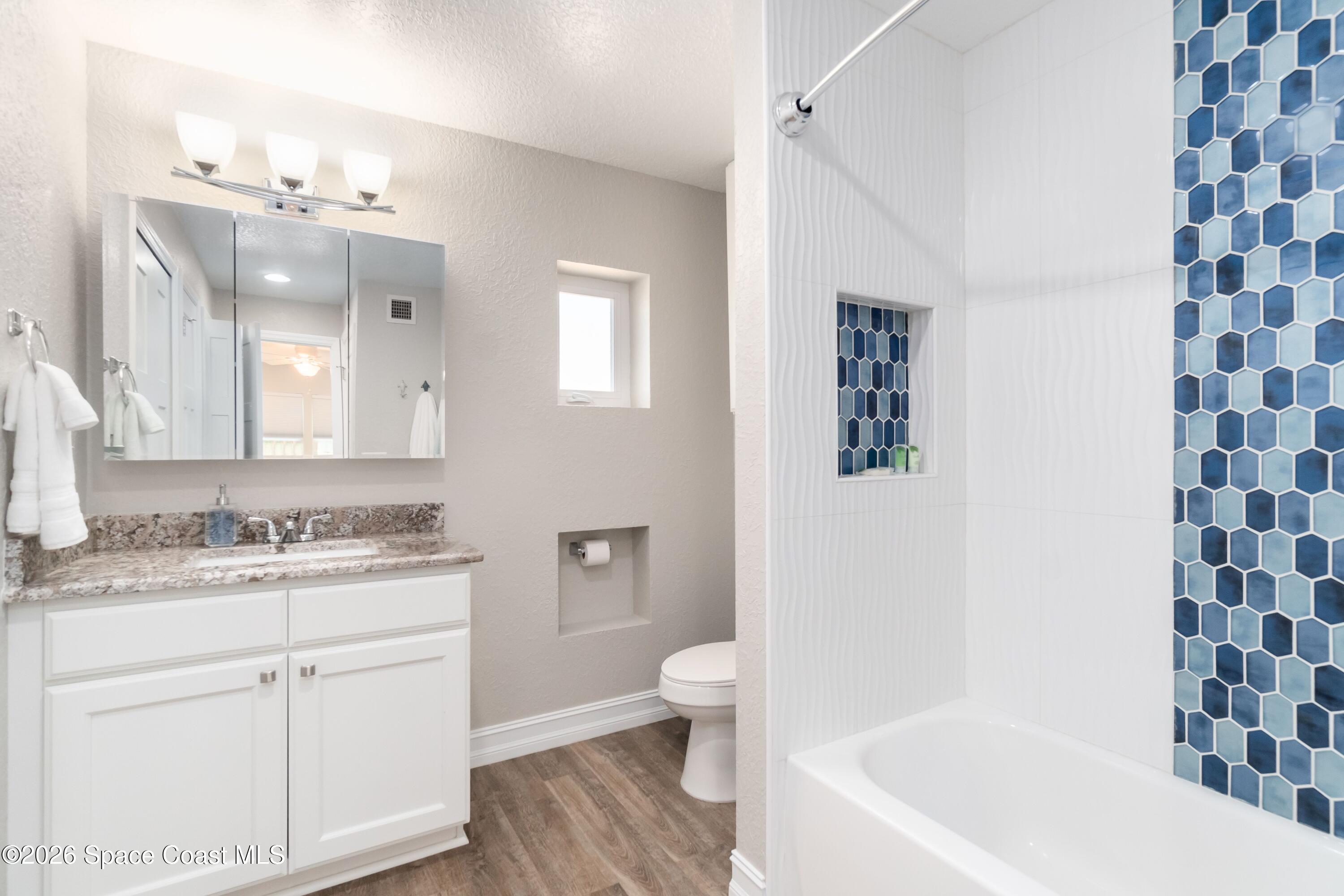 1981 Guava Avenue, Unit 104 Melbourne, FL 32935 - Photo 7 of 20 a bathroom with a sink a toilet a mirror and shower