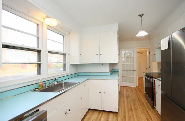 a kitchen with a refrigerator a sink and wooden floor