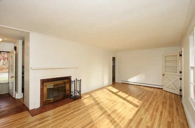 a view of empty room with wooden floor and fireplace