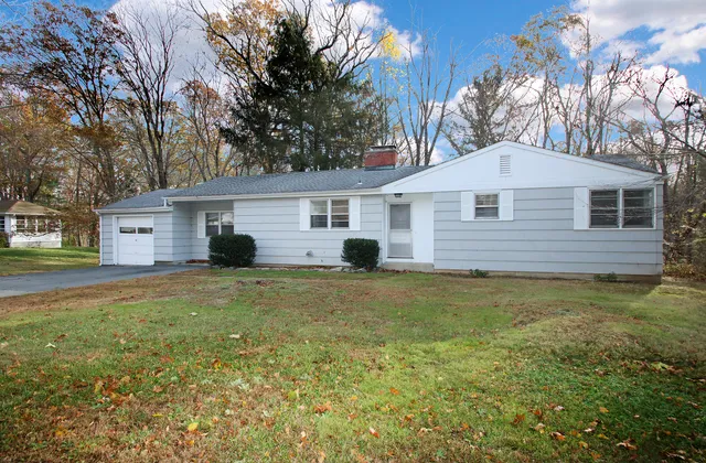 a front view of house with yard and trees in the background