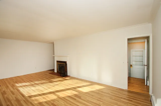 a big room with wooden floor and bathroom view