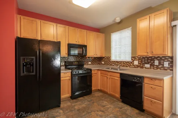 a kitchen with stainless steel appliances granite countertop a refrigerator a stove a sink and a microwave