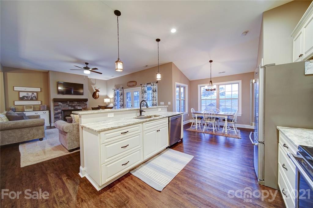 5801 Sikes Mill Road Monroe, NC 28110 - Photo 7 of 41 a large white kitchen with living room a stove a couch and a dining table with wooden floor