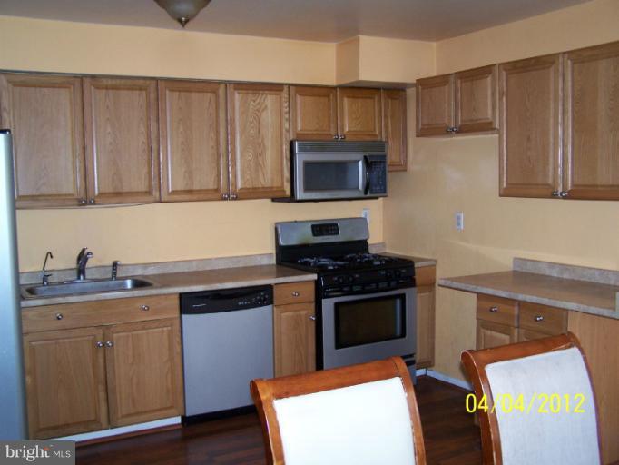 8704 Geren Road Silver Spring, MD 20901 - Photo 5 of 15 a kitchen with granite countertop a stove a sink and a microwave