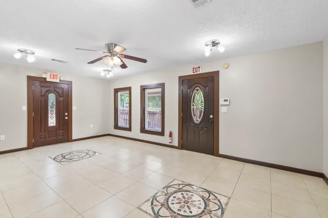 a view of an empty room with window and chandelier fan