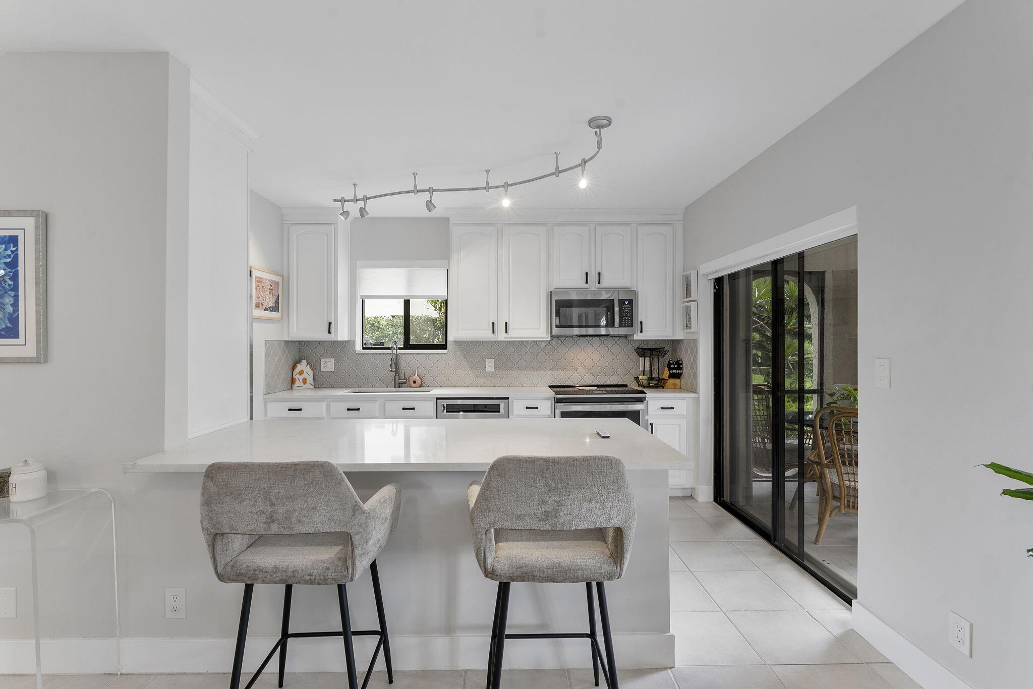 6314 Longboat Lane West, Unit 102 Boca Raton, FL 33433 - Photo 13 of 24 a kitchen with stainless steel appliances kitchen island granite countertop a refrigerator a stove a sink a dining table and chairs with wooden floor