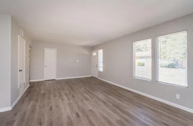 a view of an empty room with wooden floor and a window