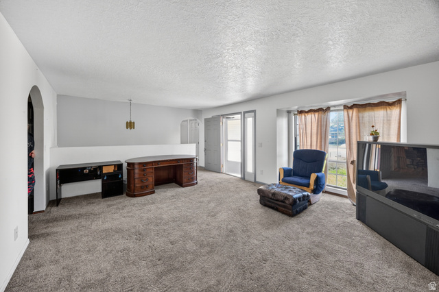 1218 East 100 South Logan, UT 84321 - Photo 11 of 23 Spacious interior room featuring light gray carpeting, neutral wall colors, and a bay window with natural light