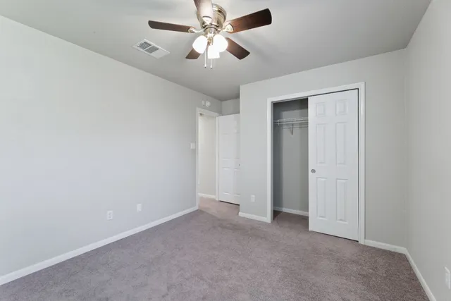 an empty room with closet and a chandelier fan