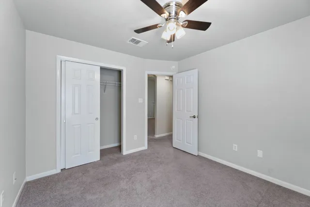 an empty room with chandelier fan and windows