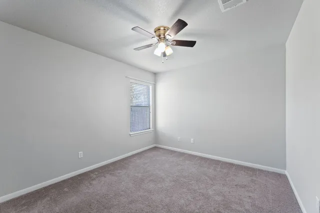 an empty room with a window and a fan