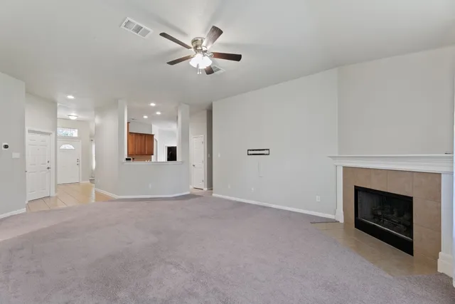 an empty room with chandelier fan and fireplace