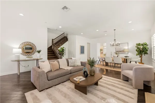 a living room with furniture and a dining table with wooden floor