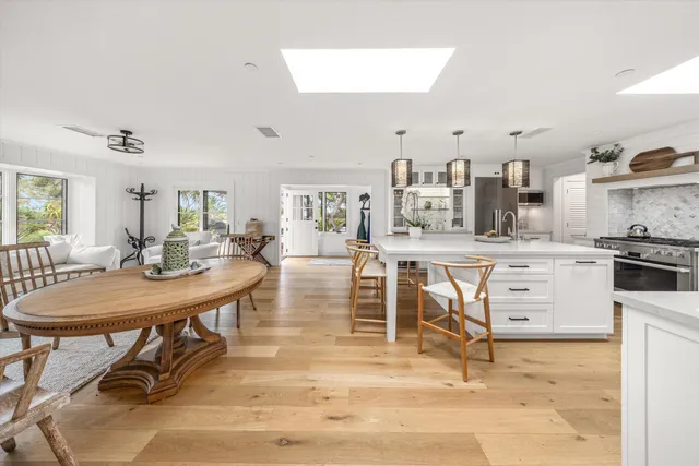 a kitchen with stainless steel appliances kitchen island granite countertop a table chairs sink and cabinets
