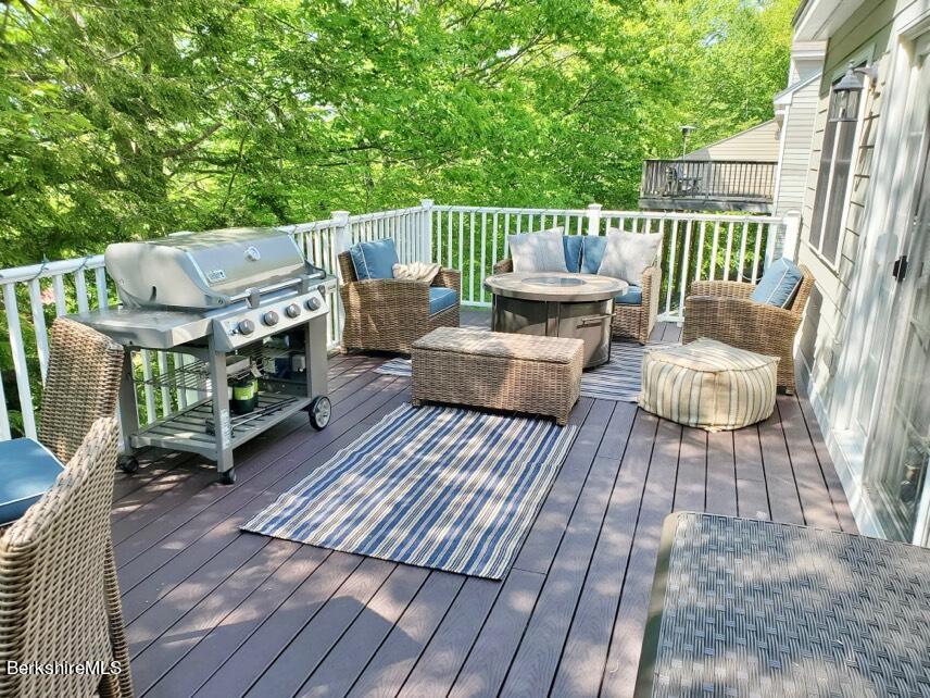 9212 Mountainside Drive Hancock, MA 01237 - Photo 43 of 44 a view of deck with table and chairs couches with wooden floor and fence