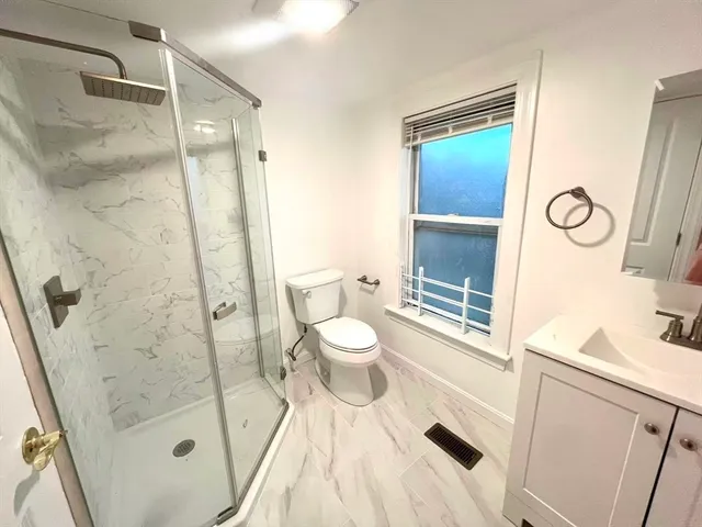 a bathroom with a sink a toilet a mirror and shower