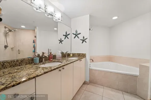 a bathroom with a granite countertop sink a large mirror and a bathtub