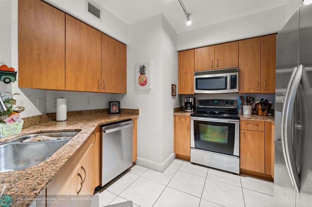1830 Radius Drive, Unit 1017 Hollywood, FL 33020 - Photo 7 of 37 a kitchen with stainless steel appliances granite countertop a stove a sink and a microwave