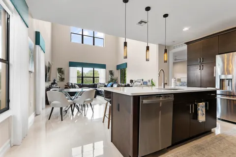 a kitchen with stainless steel appliances kitchen island granite countertop a refrigerator a oven a sink with a dining table and chairs