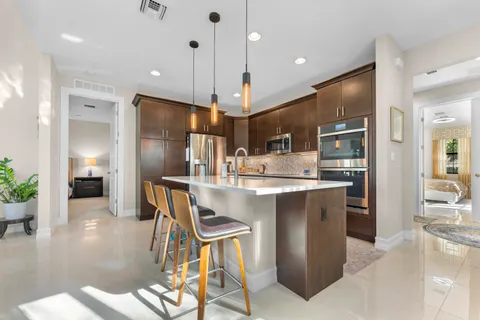 a kitchen with stainless steel appliances kitchen island granite countertop a table chairs and a refrigerator