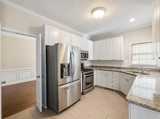 a kitchen with granite countertop stainless steel appliances a refrigerator a stove top oven and sink