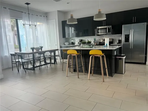 a kitchen with stainless steel appliances granite countertop a refrigerator a sink a stove and chairs