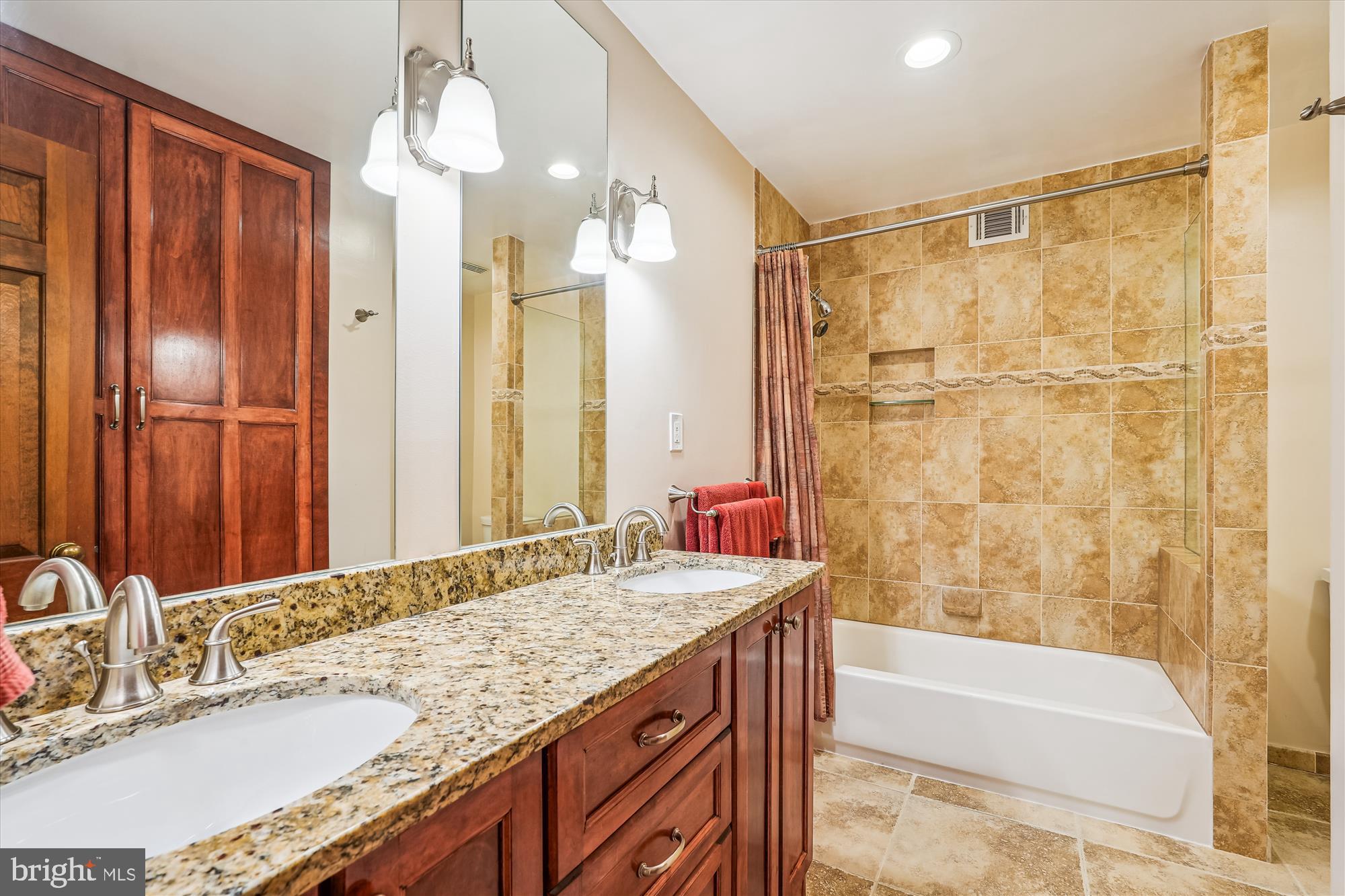 16523 Kipling Road Rockville, MD 20855 - Photo 25 of 50 a bathroom with a granite countertop sink a mirror a bathtub and shower