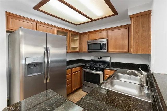 a kitchen with stainless steel appliances granite countertop a stove a refrigerator and a sink
