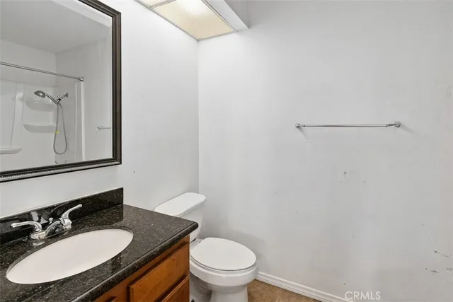 a bathroom with a granite countertop sink toilet a mirror and vanity
