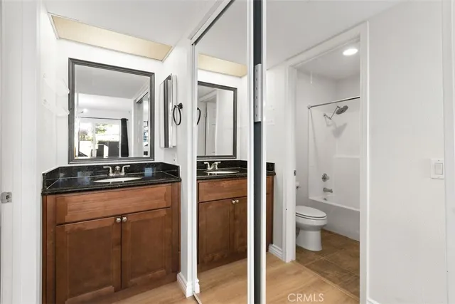 a bathroom with a granite countertop sink a toilet and a mirror