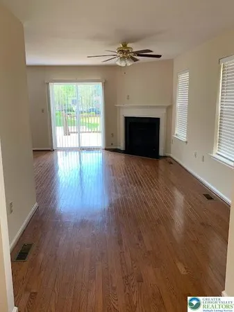 an empty room with wooden floor fireplace and windows