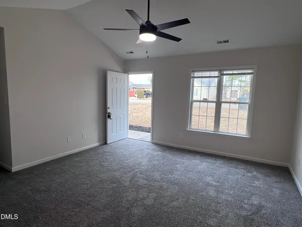 an empty room with chandelier fan and windows
