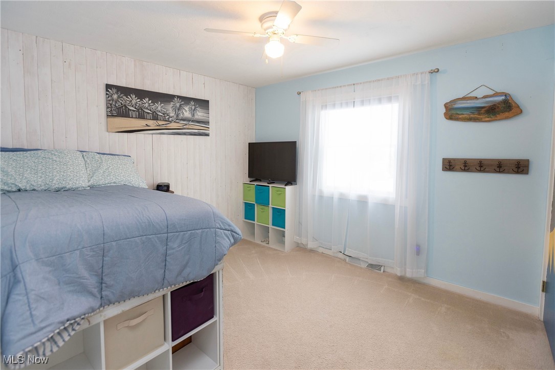 253 Sunset Road Avon Lake, OH 44012 - Photo 25 of 33 Bedroom with ceiling fan, wood walls, and light colored carpet