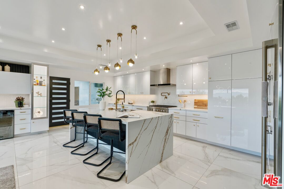 4854 Brewster Drive Tarzana, CA 91356 - Photo 23 of 60 a kitchen with stainless steel appliances kitchen island granite countertop a table chairs sink and cabinets