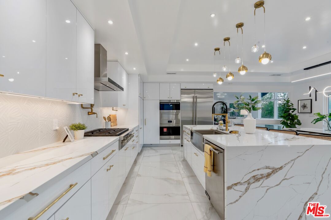4854 Brewster Drive Tarzana, CA 91356 - Photo 25 of 60 a large kitchen with stainless steel appliances kitchen island a large counter top a stove a chimney a sink and a refrigerator
